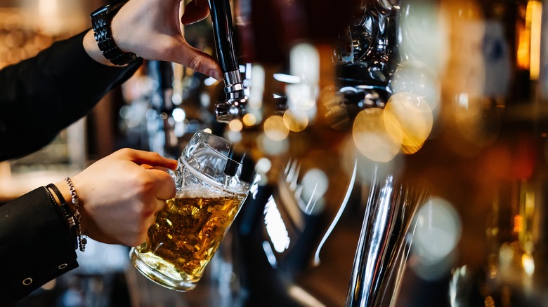 hand holding beer glass to tap