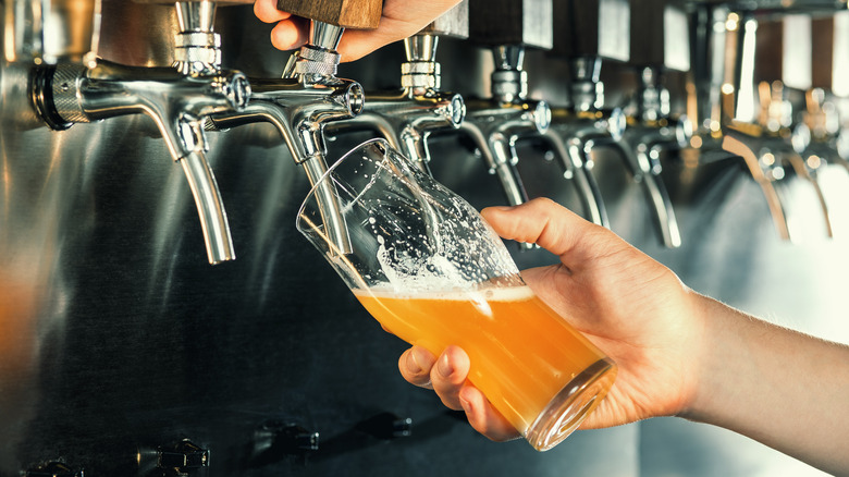 hand holding beer glass to tap