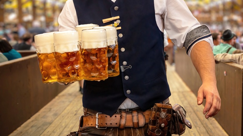 waiter holding five beer steins