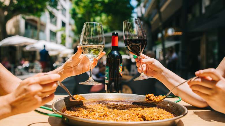 wine cheers over paella plate