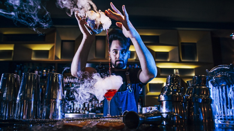 bartender pouring smoking red cocktail