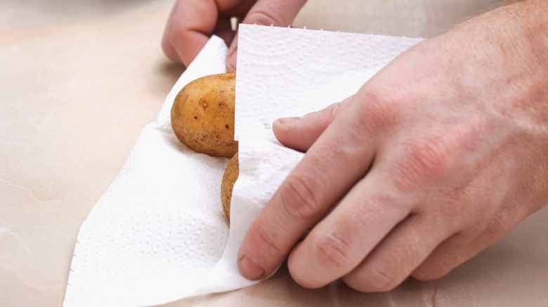 Person drying potatoes with towel 