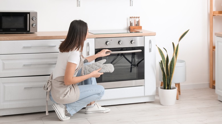 Woman opening oven in kitchen