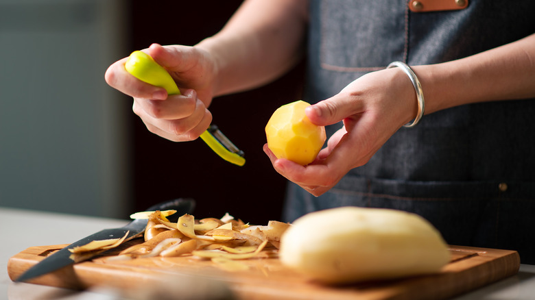 Woman peeling and cutting potatoes