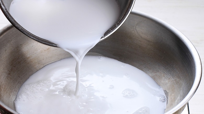 Pouring coconut milk in pot