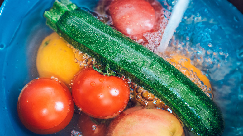 washing zucchini, tomatoes, and oranges