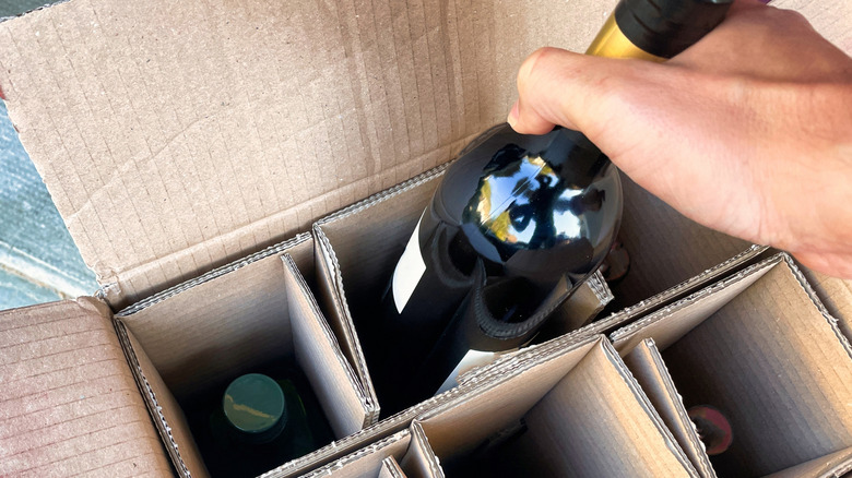Hand unpacking wine bottle from box