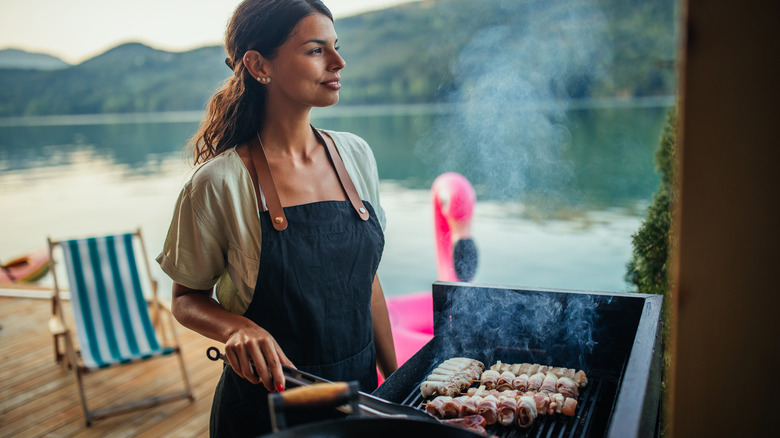 Woman barbecuing meat lakeside