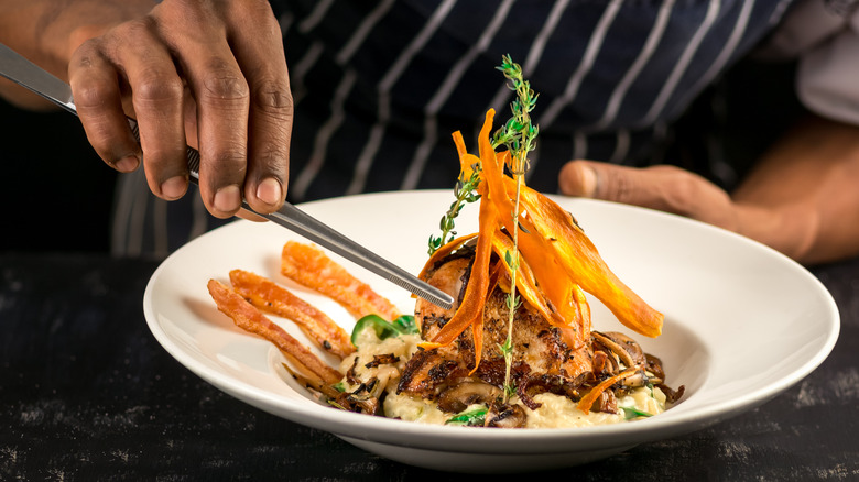 Chef finishing a dish with plating tongs