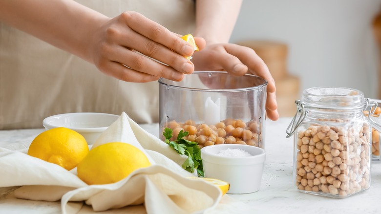 Person squeezing lemon onto chickpeas