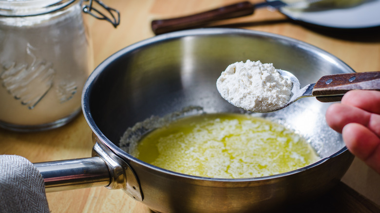 Spoon pouring flour into butter