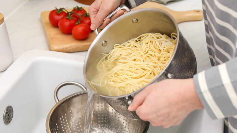 person pouring pasta into colander