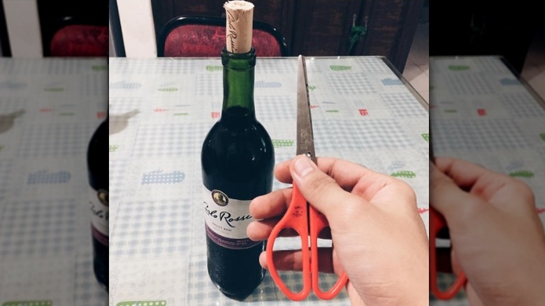 holding scissors with wine bottle