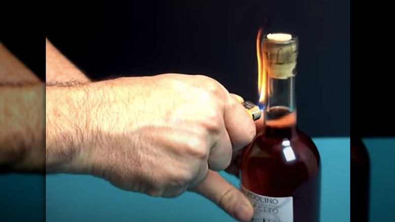 hand holding lighter on bottle