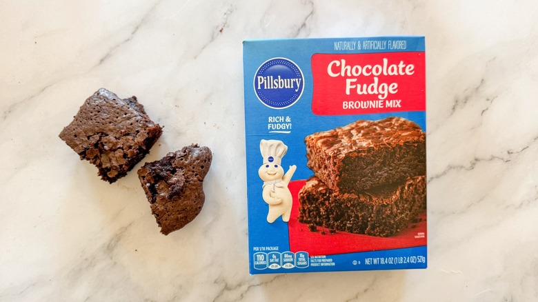 Pillsbury chocolate fudge brownie mix with brownie on marble surface