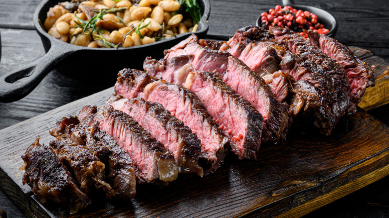 Sliced ribeye steak on a wooden carving board