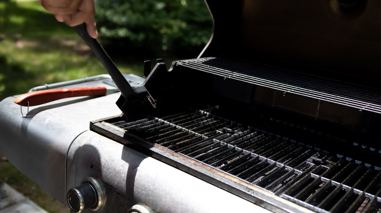 Person cleaning grill with brush