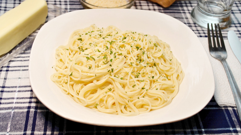 Bowl of cheesy angel hair pasta with finely chopped herbs on top