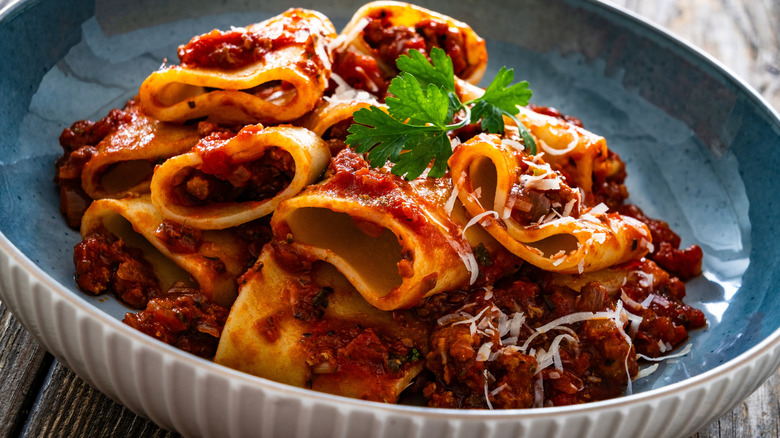 large pasta with a rich Bolognese sauce, shown in a white ceramic bowl with a blue interior glaze