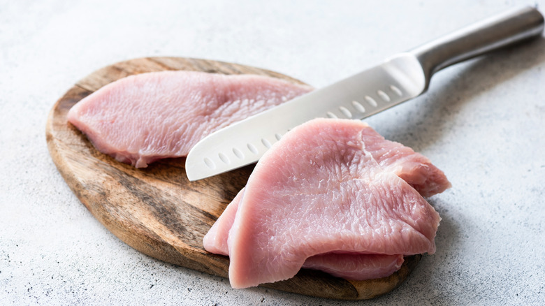 raw turkey breast cutlets, on a cutting board, with slicing knife