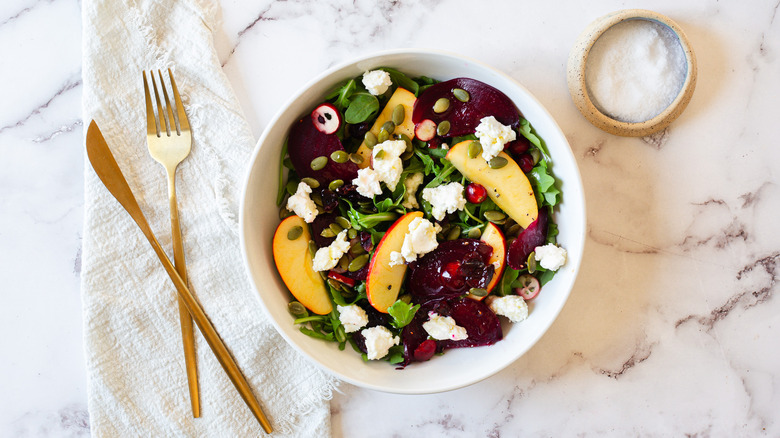 beet and fruit salad bowl with cutlery and salt