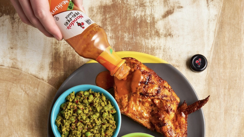 Pouring Nando's peri peri sauce on chicken