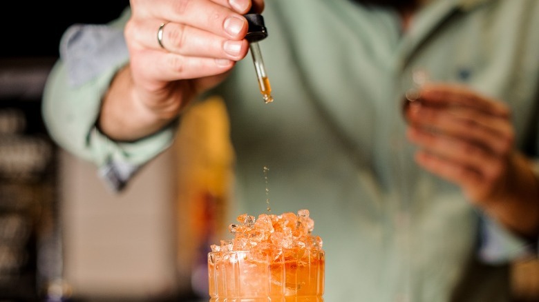 Bartender adding bitters to cocktail