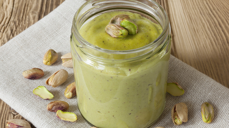 jar of pistchio cream with piastchios on the side