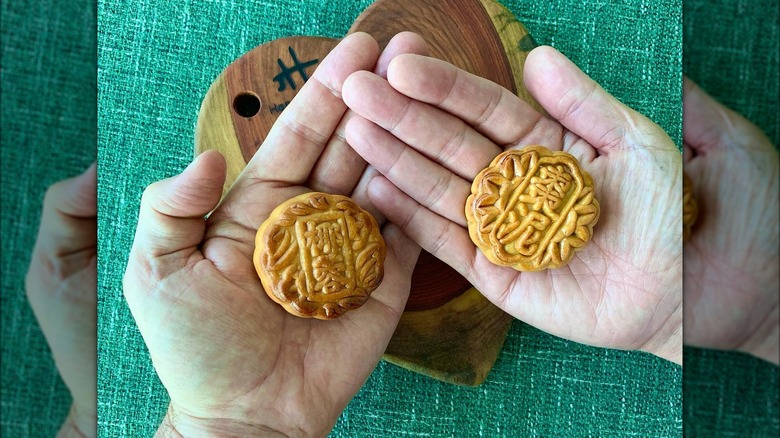 two hands holding mooncakes