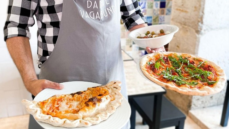 Waiter holding a pizza and calzone