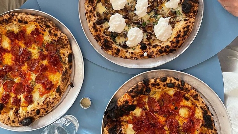 Three pizzas on blue tables