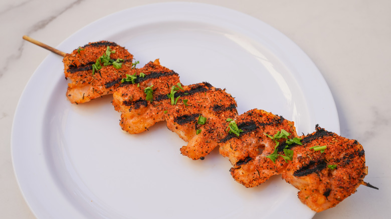 A white plate with cajun-spiced grilled shrimp