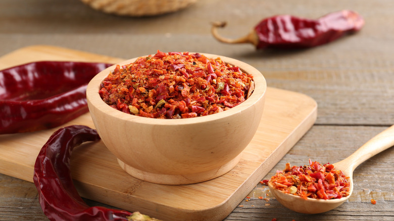 Chile flakes in a bowl and spoon with whole dried chiles around them