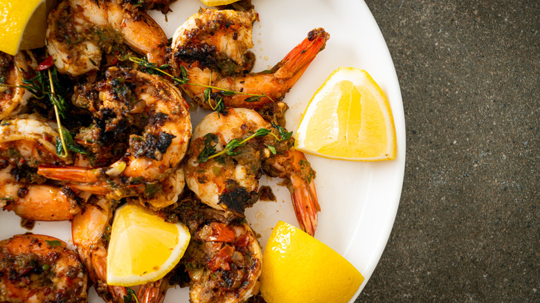 A plate of jerk shrimp with lemon wedges