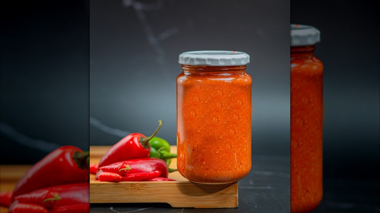 Jar of piri piri with fresh chiles on the side
