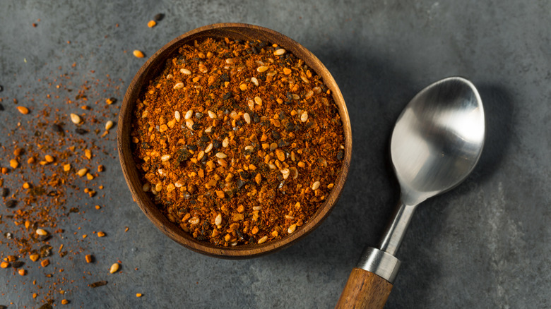 Togarashi blend in a wooden bowl with a metal spoon next to it