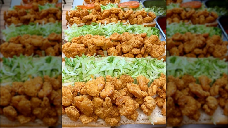 Three open-faced po'boys in kitchen loaded with fried shrimp and lettuce