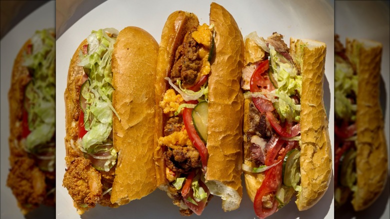 Three different po'boys side-by-side on white plate