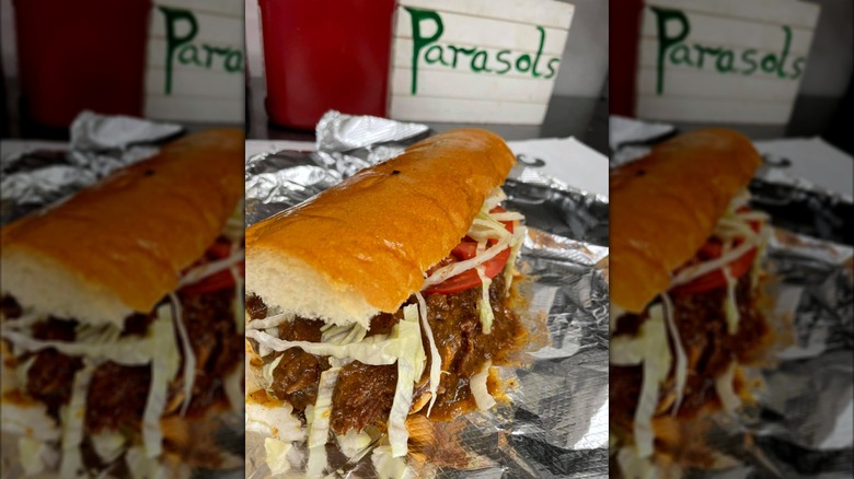 Sloppy roast beef po'boy on foil with Parasol's sign in background