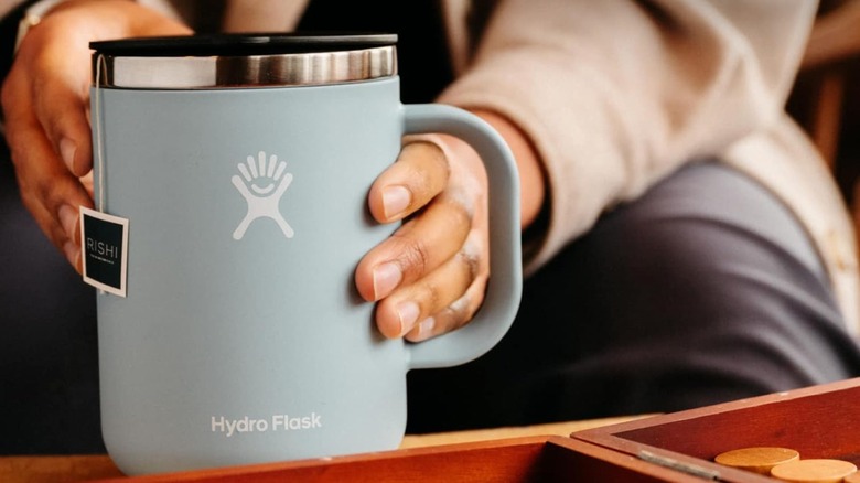 Hand holding a blue Hydro Flask Travel Mug