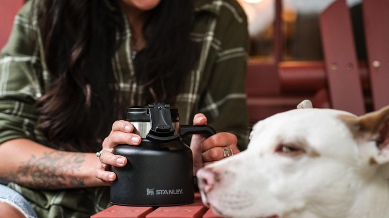 Woman holding a Stanley Admiral's mug while sitting next to her dog