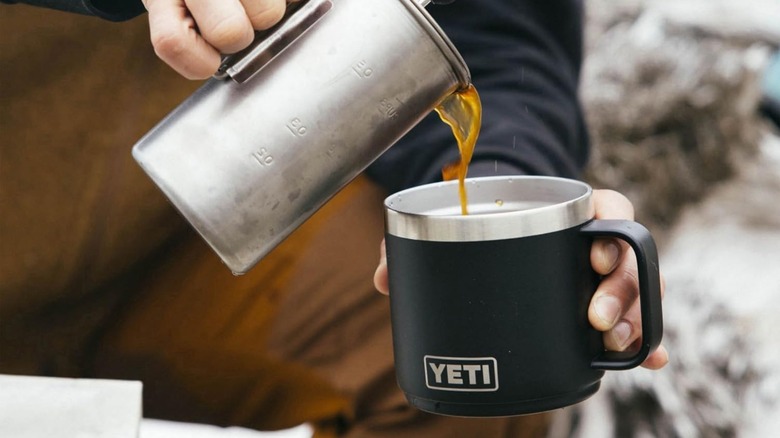 Person pouring coffee into a Yeti Rambler outside