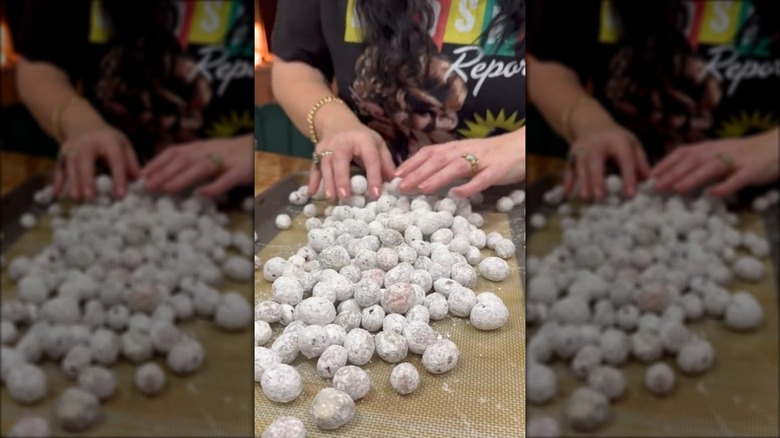 Hands spreading sugar-coated cranberries out on a baking sheet