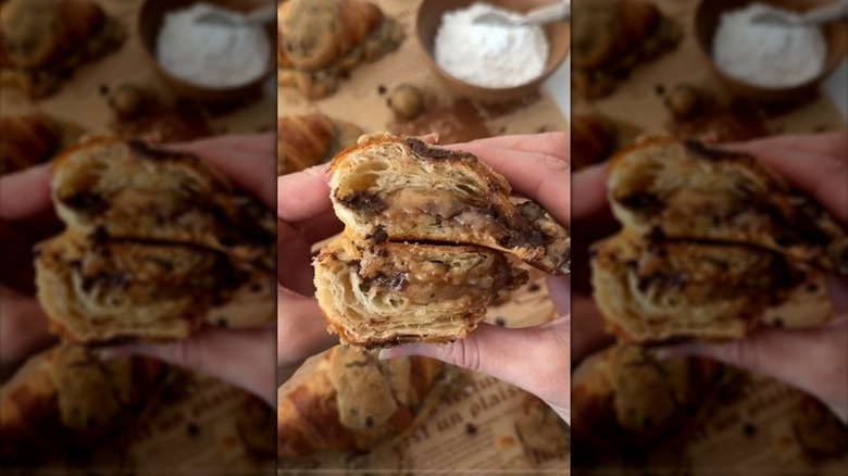 Hands holding halved cookie-stuffed croissant