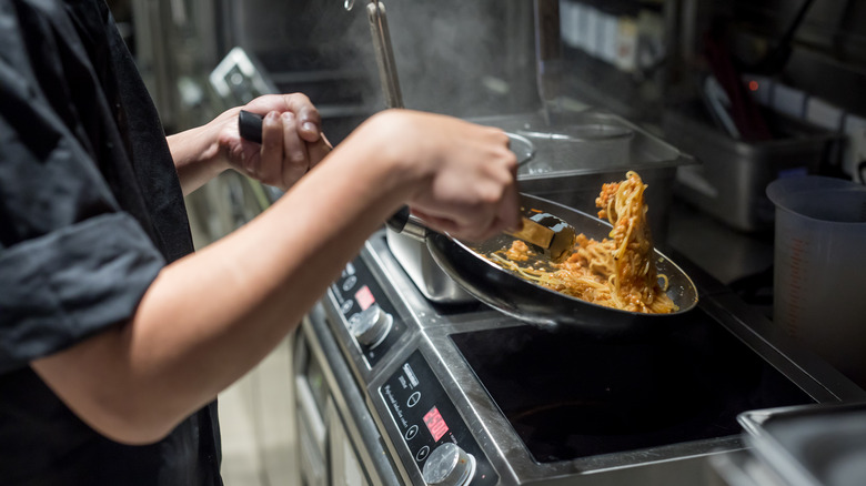 Chef tossing spaghetti in sauce