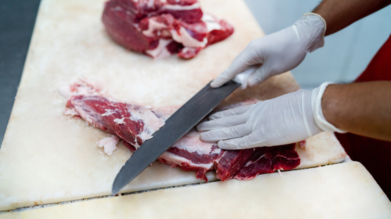 Butcher trimming meat