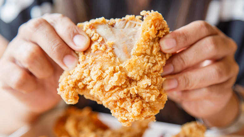 Hands splitting fried chicken