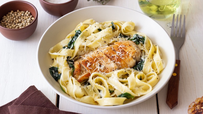 Plated bowl of pasta with chicken breast on top