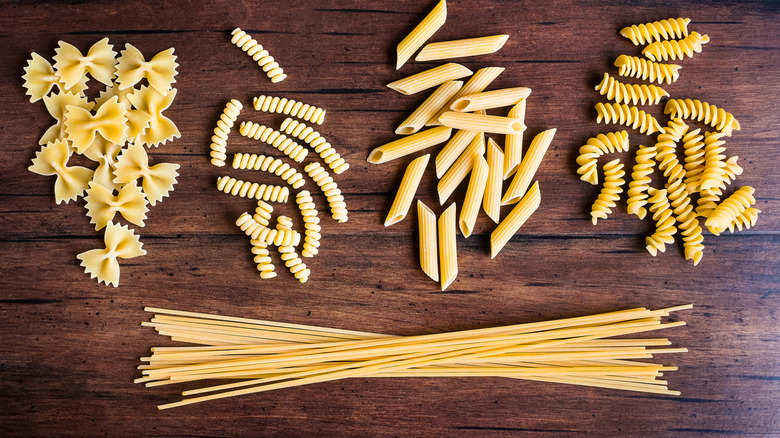 Variety of pasta shapes on wooden board