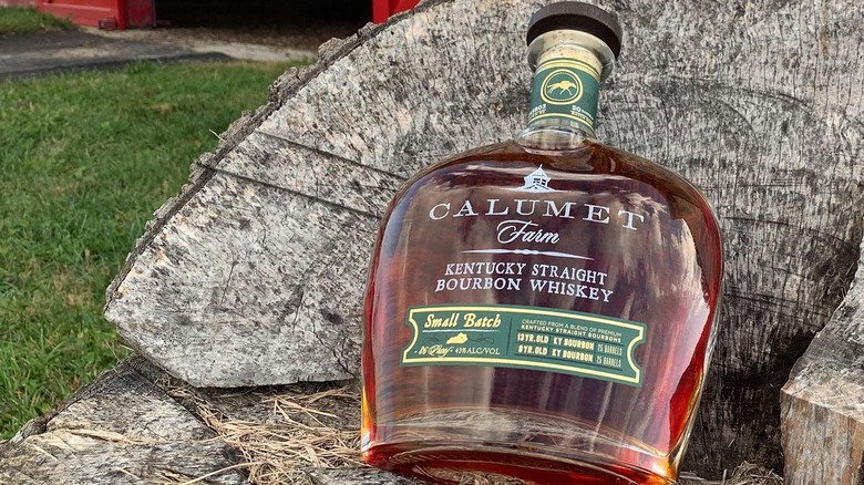 Bottle of Calumet bourbon on wood with greenery in the back